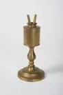 Brass lamp that resembles a large candlestick with a reservoir and two wick holders at the top in the shape of a V.