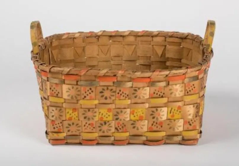 Oval-shaped splint woven basket with handles, stamped with flowers and dots with additional yellow, orange and green patterns interwoven on some splints.